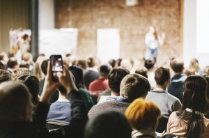 Crowd of people listening to woman on stage